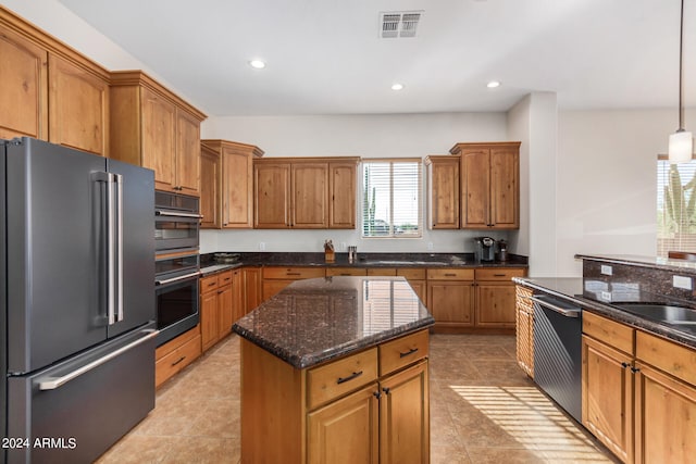 kitchen featuring pendant lighting, dark stone counters, a center island, stainless steel appliances, and light tile patterned floors