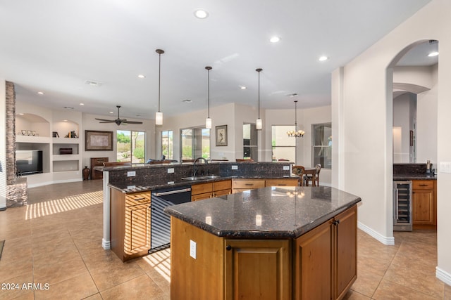 kitchen featuring a spacious island, black dishwasher, hanging light fixtures, and dark stone countertops