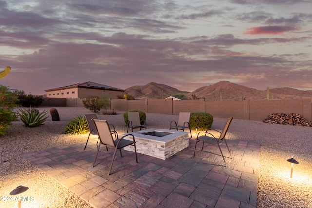 patio terrace at dusk featuring an outdoor fire pit and a mountain view