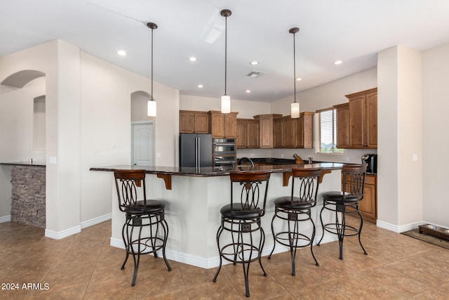 kitchen featuring appliances with stainless steel finishes, a kitchen breakfast bar, light tile patterned floors, pendant lighting, and a large island