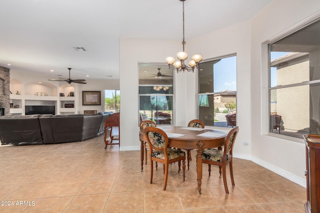 dining space featuring ceiling fan with notable chandelier, built in shelves, and light tile patterned floors