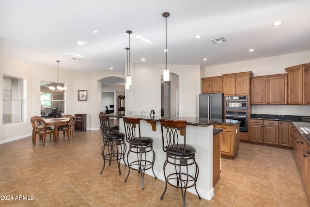 kitchen with hanging light fixtures, appliances with stainless steel finishes, a center island, a notable chandelier, and a kitchen bar