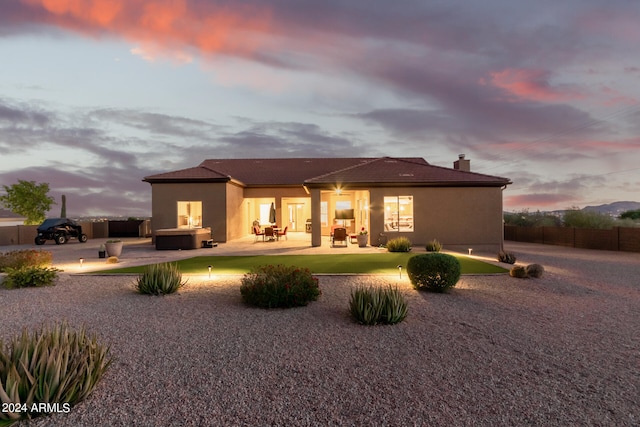 back house at dusk featuring a patio