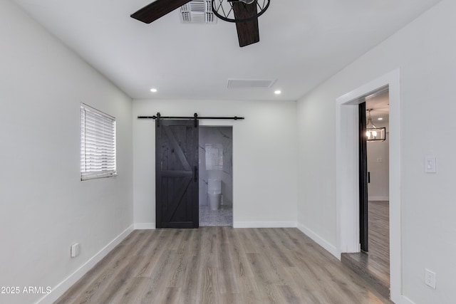 2501 E Campbell Ave, Phoenix, AZ 85016 - unfurnished bedroom featuring a barn door, wood finished floors, baseboards, recessed lighting, and ensuite bathroom