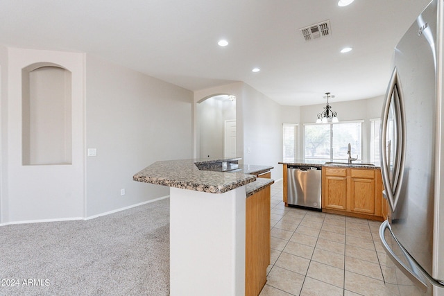 kitchen with pendant lighting, a kitchen island with sink, stainless steel appliances, light colored carpet, and a notable chandelier