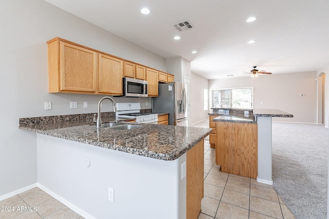 kitchen with light carpet, dark stone countertops, kitchen peninsula, and appliances with stainless steel finishes