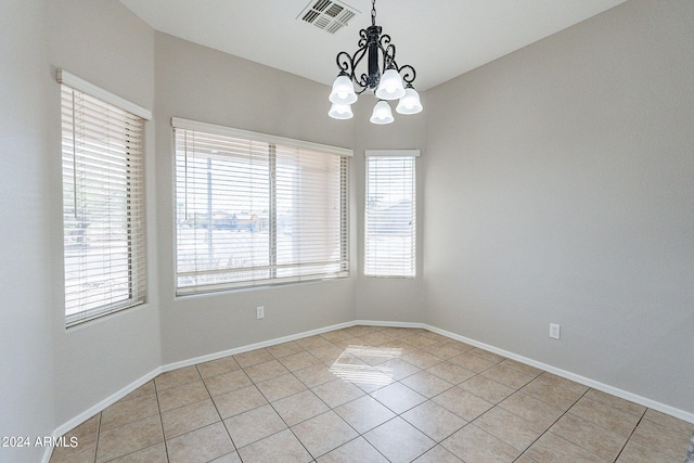 tiled empty room featuring a chandelier