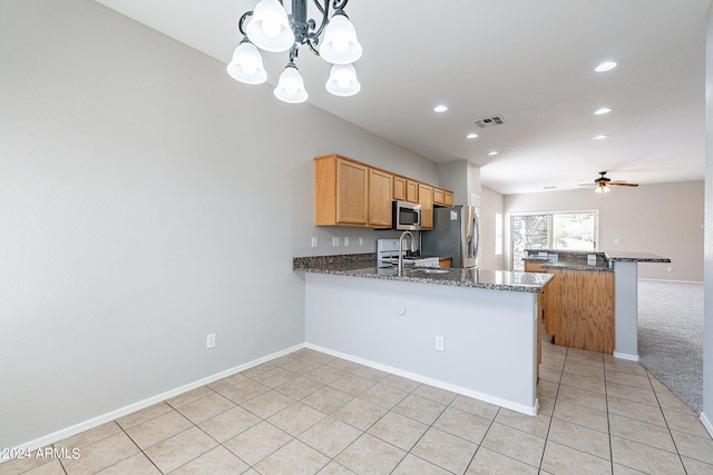 kitchen with hanging light fixtures, light tile patterned floors, kitchen peninsula, appliances with stainless steel finishes, and dark stone countertops