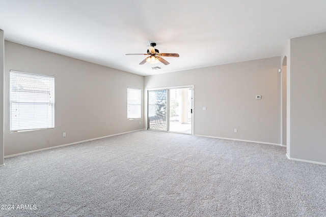 carpeted spare room with a wealth of natural light and ceiling fan