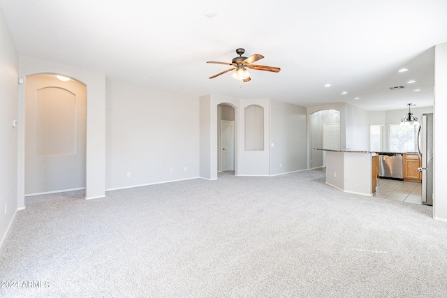 unfurnished living room featuring light colored carpet and ceiling fan with notable chandelier