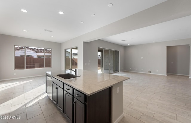 kitchen featuring light stone countertops, sink, an island with sink, and stainless steel dishwasher