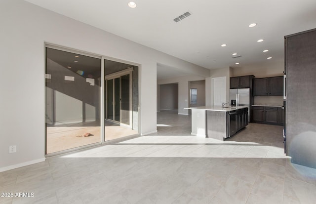 kitchen with light tile patterned flooring, sink, an island with sink, and stainless steel refrigerator with ice dispenser