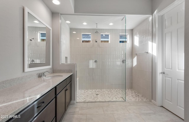 bathroom with tiled shower, vanity, and tile patterned flooring