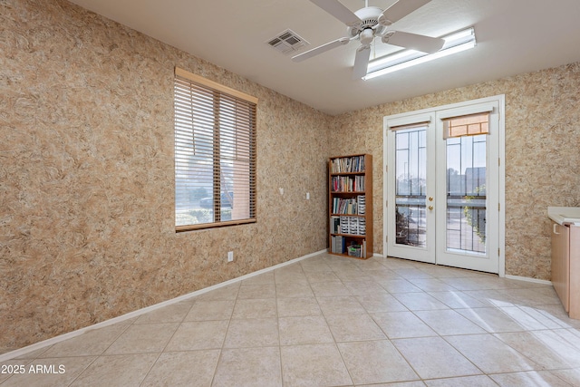 tiled empty room featuring french doors and ceiling fan