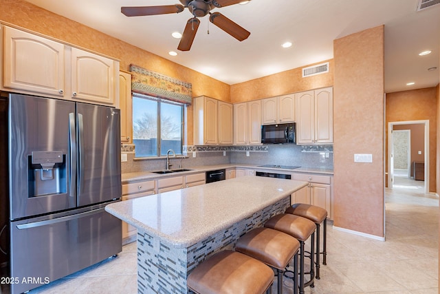 kitchen with a breakfast bar, tasteful backsplash, sink, a center island, and black appliances