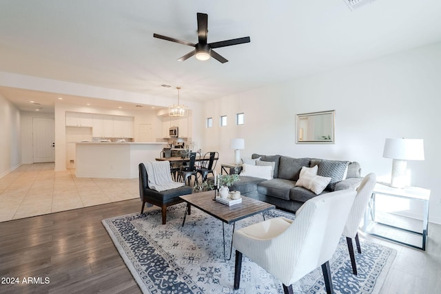 living room with light hardwood / wood-style flooring and ceiling fan with notable chandelier