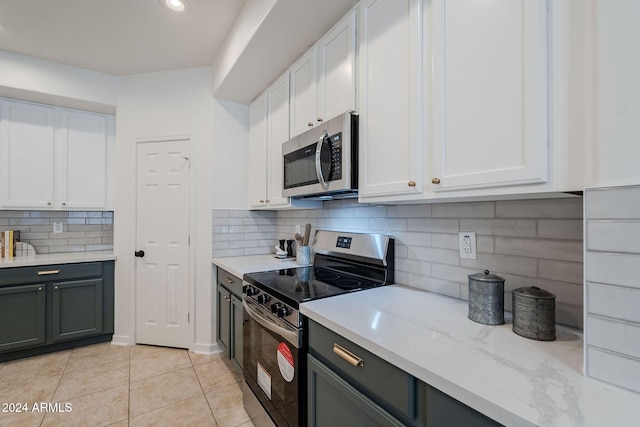 kitchen with appliances with stainless steel finishes, light tile patterned floors, white cabinetry, and light stone counters