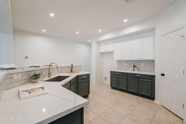 kitchen featuring light stone countertops, sink, light tile patterned flooring, decorative backsplash, and white cabinets