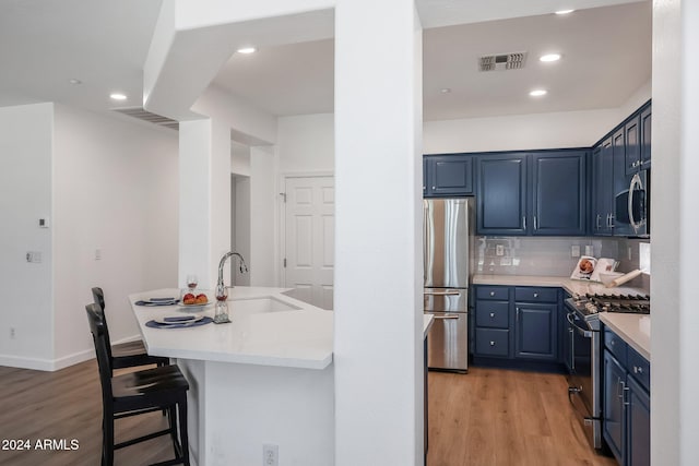 kitchen with appliances with stainless steel finishes, light hardwood / wood-style flooring, blue cabinets, and sink