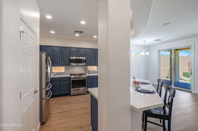 kitchen with stainless steel appliances, decorative light fixtures, light hardwood / wood-style flooring, tasteful backsplash, and a notable chandelier