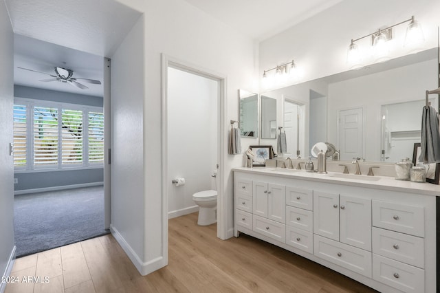 bathroom with hardwood / wood-style floors, toilet, ceiling fan, and dual bowl vanity