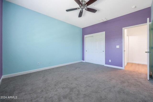 unfurnished bedroom featuring ceiling fan, a closet, and carpet flooring