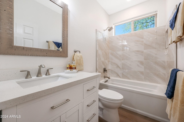 full bathroom with tiled shower / bath, vanity, hardwood / wood-style floors, and toilet