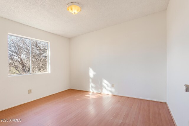 unfurnished room with a textured ceiling and light hardwood / wood-style floors
