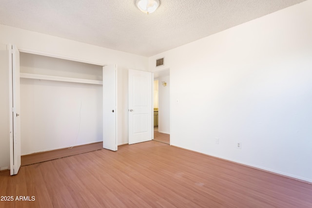unfurnished bedroom with a closet, hardwood / wood-style floors, and a textured ceiling