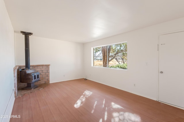 unfurnished living room featuring a wood stove and light wood-type flooring