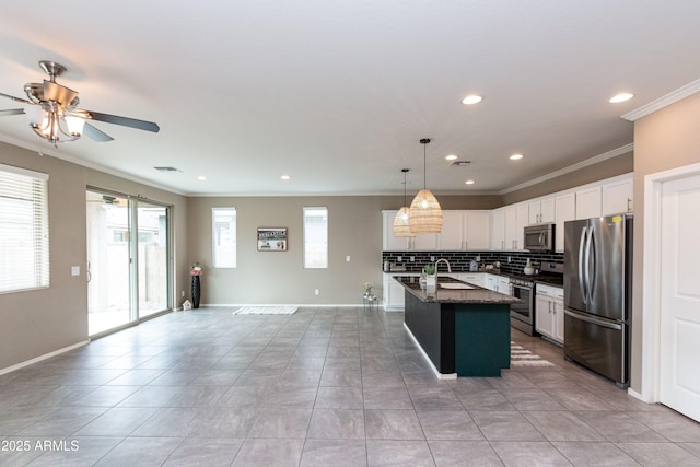 kitchen featuring sink, appliances with stainless steel finishes, white cabinetry, a center island with sink, and decorative light fixtures
