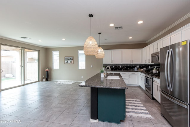 kitchen with appliances with stainless steel finishes, white cabinetry, an island with sink, sink, and ornamental molding