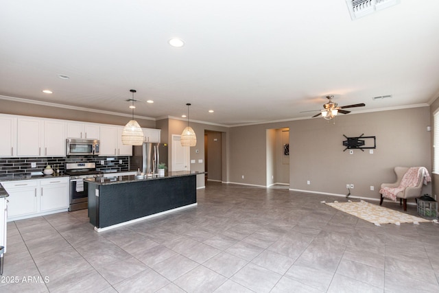kitchen with hanging light fixtures, stainless steel appliances, white cabinets, a center island with sink, and decorative backsplash