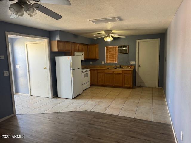 kitchen featuring white appliances, ceiling fan, light countertops, and brown cabinetry