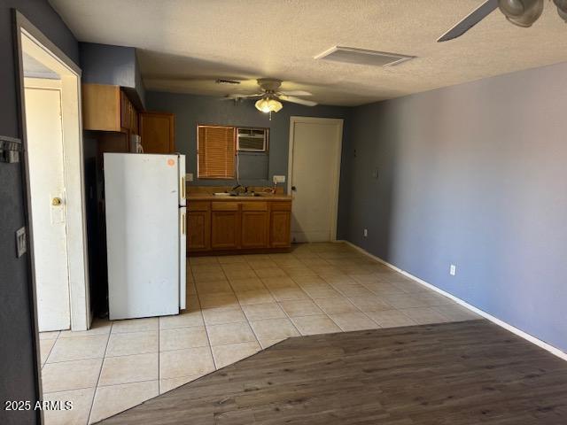 kitchen with brown cabinetry, freestanding refrigerator, and a ceiling fan