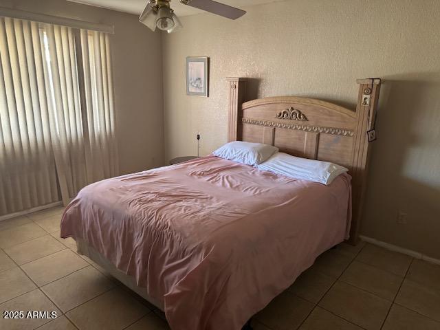 bedroom featuring tile patterned flooring, a ceiling fan, and baseboards