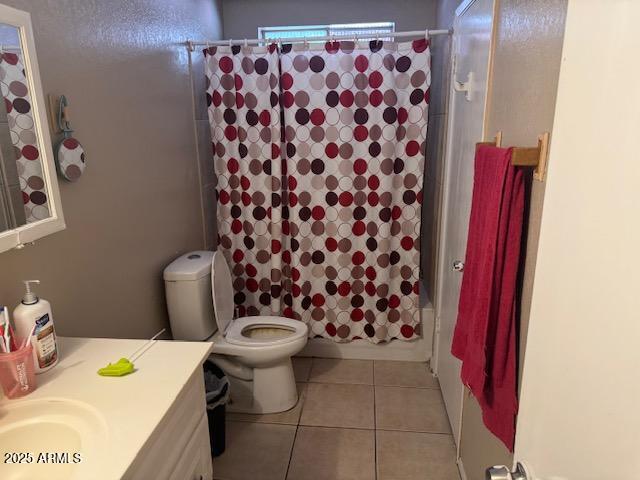 bathroom featuring vanity, shower / bathtub combination with curtain, toilet, and tile patterned floors