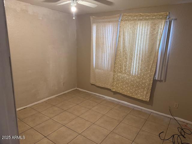 spare room featuring light tile patterned floors, baseboards, and a ceiling fan