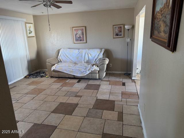 living area with ceiling fan and baseboards