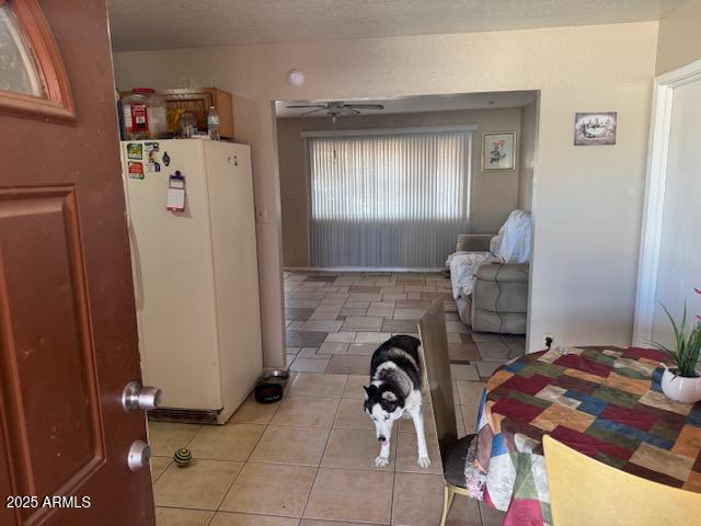 interior space with freestanding refrigerator, light tile patterned flooring, and a textured ceiling