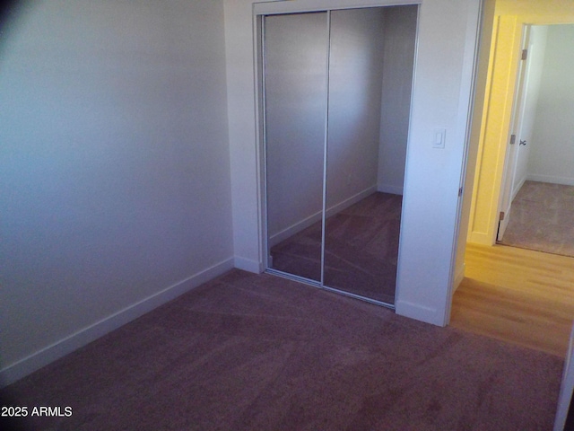 unfurnished bedroom featuring baseboards, a closet, and carpet