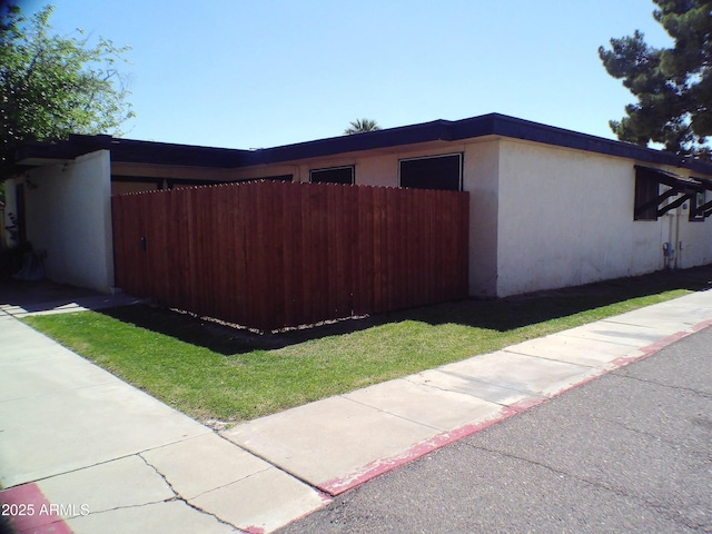view of side of property featuring stucco siding and fence