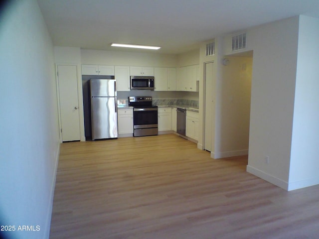 kitchen featuring baseboards, visible vents, light wood-style floors, white cabinets, and appliances with stainless steel finishes