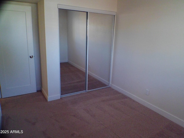 unfurnished bedroom featuring carpet floors, a closet, and baseboards