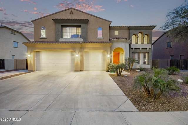 mediterranean / spanish-style home featuring an attached garage, fence, driveway, and stucco siding