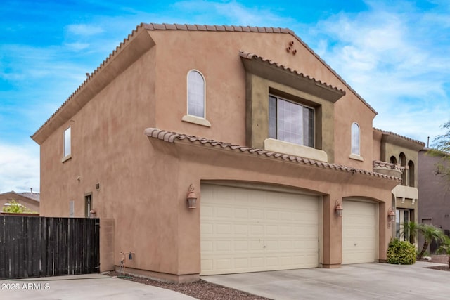 view of front of home featuring stucco siding, driveway, a garage, and fence