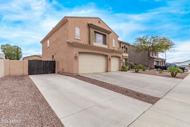 view of front facade featuring a gate, driveway, an attached garage, stucco siding, and a tile roof