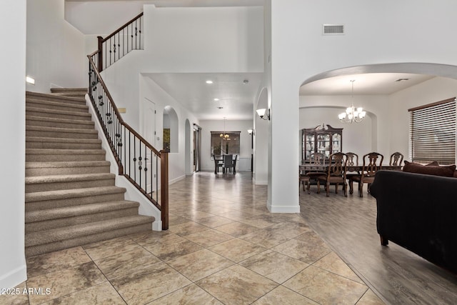 foyer with a notable chandelier, arched walkways, visible vents, and a towering ceiling