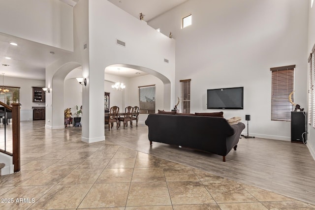 living area with light tile patterned floors, visible vents, arched walkways, and a chandelier