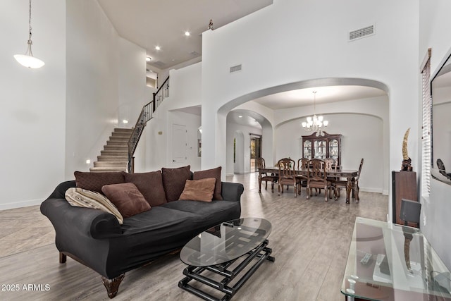 living area featuring arched walkways, visible vents, a high ceiling, and wood finished floors